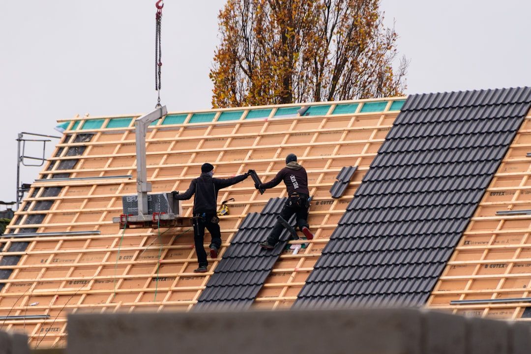 Roofers installing clay tiles on a pitched roof