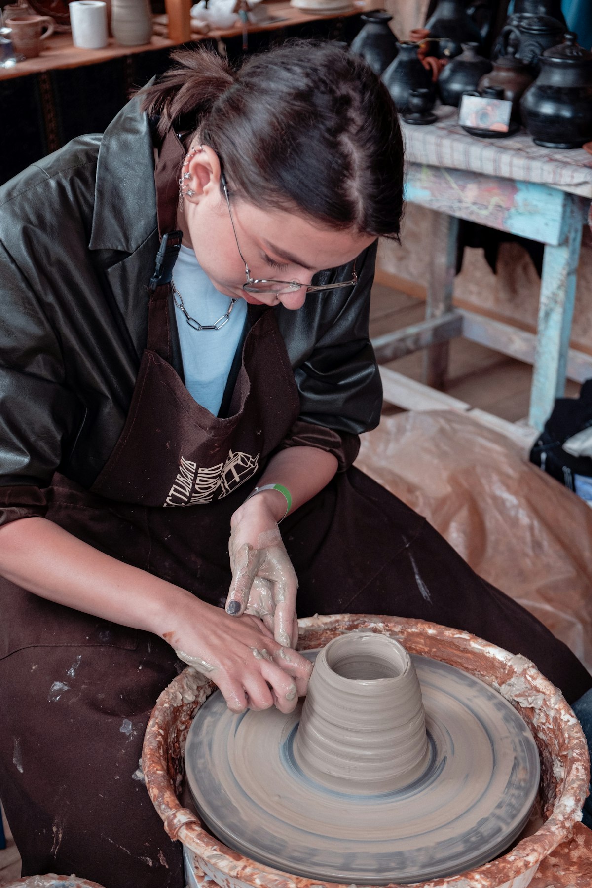 A woman in an apron meticulously hand-finishing a green-state clay piece in the workshop